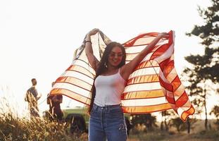 fühlt Freiheit. freunde haben ein schönes wochenende im freien in der nähe ihres grünen autos mit usa-flagge foto