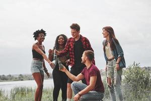 Bier trinken. gruppe von menschen picknickt am strand. Freunde haben Spaß am Wochenende foto