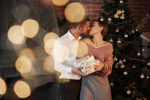 Vorderansicht. Weihnachtsgeschenk für die Frau. Herr im klassischen Anzug überreicht seiner Frau das Geschenk foto