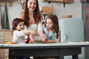 Dass Kinder Süßigkeiten lieben, ist bekannt. junge schöne frau gibt die kekse, während sie mit spielzeug am tisch sitzen foto