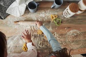 einmal werden sie große Köche werden. jetzt viel Spaß. Draufsicht auf Kinder, die lernen, mit speziell geformten Instrumenten Essen aus dem Mehl zuzubereiten foto