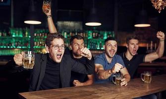 es ist ein Ziel. Sieg feiern. drei Sportfans in einer Bar beim Fußball schauen. mit Bier in der Hand foto