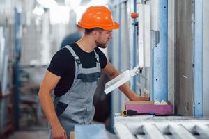 in der Nähe des Computers. Industriearbeiter drinnen in der Fabrik. junger Techniker mit orangefarbenem Schutzhelm foto