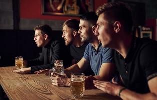 drei Sportfans in einer Bar beim Fußball schauen. mit Bier in der Hand foto