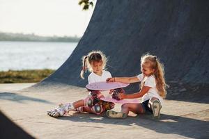 neuen Schlittschuh ausprobieren. Zwei süße weibliche Kinder haben Spaß im Freien im Park foto