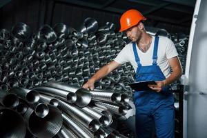 prüft die Qualität des Materials. Mann in Uniform arbeitet an der Produktion. Industrielle moderne Technologie foto