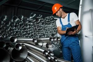 schaut genauer hin. Mann in Uniform arbeitet an der Produktion. Industrielle moderne Technologie foto