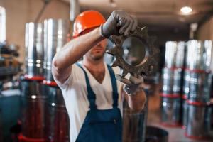 mechanisches Getriebe. Mann in Uniform arbeitet an der Produktion. Industrielle moderne Technologie foto