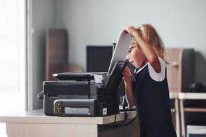 Arbeitsprozess. Mädchen hält Papier und legt es in den Drucker foto