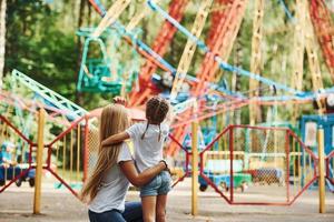 einander umarmen. Fröhliches kleines Mädchen, ihre Mutter, hat eine gute Zeit im Park zusammen in der Nähe von Sehenswürdigkeiten foto