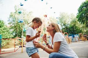 Eis essen. Fröhliches kleines Mädchen, ihre Mutter, hat eine gute Zeit im Park zusammen in der Nähe von Sehenswürdigkeiten foto