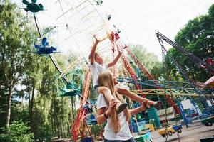 Gehen mit Tochter auf den Schultern. Fröhliches kleines Mädchen, ihre Mutter, hat eine gute Zeit im Park zusammen in der Nähe von Sehenswürdigkeiten foto