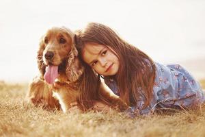 sich glücklich fühlen und das Haustier umarmen. süßes kleines Mädchen geht an sonnigen Tagen mit ihrem Hund im Freien spazieren foto