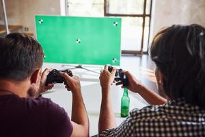 Bier auf dem Tisch. eine gruppe von freunden hat spaß beim konsolenspiel drinnen im wohnzimmer foto