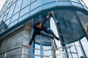 junger Mann, der tagsüber Parkour in der Stadt macht. Konzeption von Extremsportarten foto