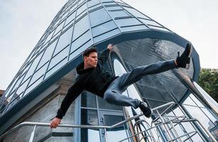 junger Mann, der tagsüber Parkour in der Stadt macht. Konzeption von Extremsportarten foto