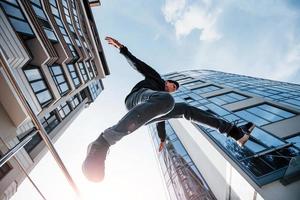 junger Mann, der tagsüber Parkour in der Stadt macht. Konzeption von Extremsportarten foto