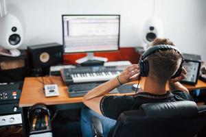 konzentriert bei der Arbeit. toningenieur mit kopfhörern, der musik drinnen im studio bearbeitet und mischt foto