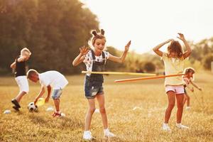 Mädchen mit Kreis-Fitness-Tool. eine gruppe von kindern hat ein aktives wochenende auf dem feld foto