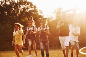 eine gruppe von kindern hat ein aktives wochenende auf dem feld. von schönem Sonnenlicht beleuchtet foto