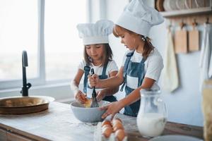 Familienkinder in weißer Kochuniform bereiten Essen in der Küche zu foto