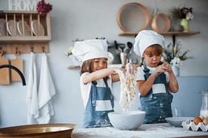 Familienkinder in weißer Kochuniform bereiten Essen in der Küche zu foto