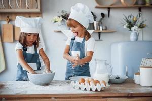 Familienkinder in weißer Kochuniform bereiten Essen in der Küche zu foto