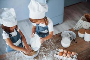 Ansicht von oben. Familienkinder in weißer Kochuniform bereiten Essen in der Küche zu foto