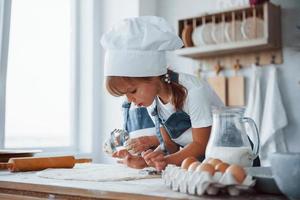 Konzentration aufs Kochen. Familienkinder in weißer Kochuniform bereiten Essen in der Küche zu foto