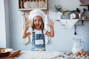 Spaß haben. süßes kind in weißer kochuniform, das essen in der küche zubereitet foto