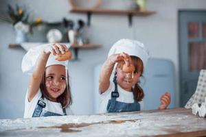 mit Eiern spielen. Familienkinder in weißer Kochuniform bereiten Essen in der Küche zu foto