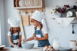 Familienkinder in weißer Kochuniform bereiten Essen in der Küche zu foto