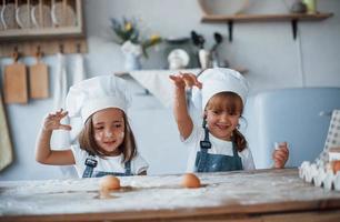 mit Eiern spielen. Familienkinder in weißer Kochuniform bereiten Essen in der Küche zu foto