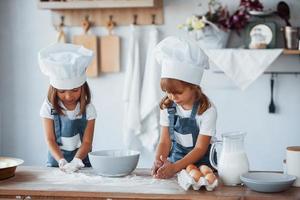 Familienkinder in weißer Kochuniform bereiten Essen in der Küche zu foto