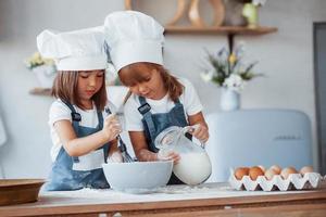 Familienkinder in weißer Kochuniform bereiten Essen in der Küche zu foto