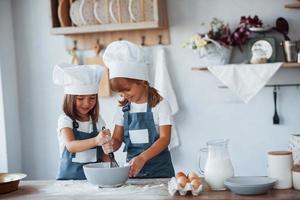 Familienkinder in weißer Kochuniform bereiten Essen in der Küche zu foto