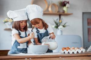 Familienkinder in weißer Kochuniform bereiten Essen in der Küche zu foto