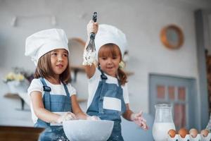 Familienkinder in weißer Kochuniform bereiten Essen in der Küche zu foto