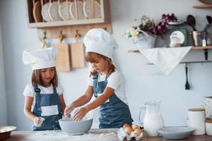 Familienkinder in weißer Kochuniform bereiten Essen in der Küche zu foto