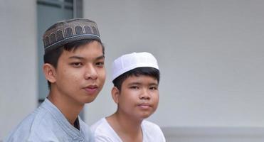 porträt asiatische muslimische oder islamische jungen, die mit muslimischen jungen in einer reihe sitzen, um zu beten oder die religiöse tätigkeit auszuüben, weicher und selektiver fokus. foto