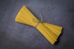 rohe Spaghetti-Nudeln ungekocht, Spaghetti-Nudeln auf dunklem Hintergrund, rohe Nudeln italienisches Essen foto