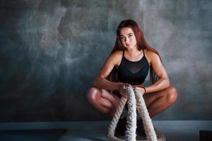 junge fitnessfrau mit schlankem körpertyp sitzt mit knoten in den händen foto