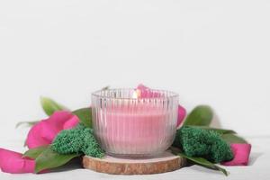 vegane Sojawachskerze auf pflanzlicher Basis im Glas. vegetarische rosa Kerze aus natürlichem Sojawachs auf Holzpodim mit Blumendekor. foto