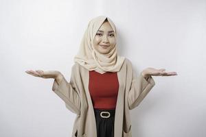 Aufgeregte asiatische Frau mit Hijab, die auf den Kopierbereich neben ihr zeigt, isoliert durch weißen Hintergrund foto
