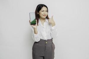 aufgeregte asiatische frau mit weißem hemd gibt daumen hoch handgeste der zustimmung, während sie kopierraum auf ihrem telefon zeigt foto