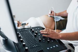 männlicher arzt macht ultraschall für eine schwangere frau im krankenhaus