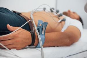 Mann, der in der Klinik auf dem Bett liegt und Elektrokardiogramm-Test erhält foto