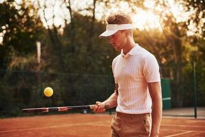 junger tennisspieler in sportlicher kleidung ist draußen auf dem platz foto