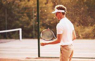 junger tennisspieler in sportlicher kleidung ist draußen auf dem platz foto