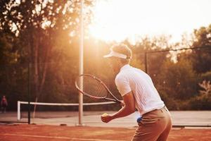 junger tennisspieler in sportlicher kleidung ist draußen auf dem platz foto